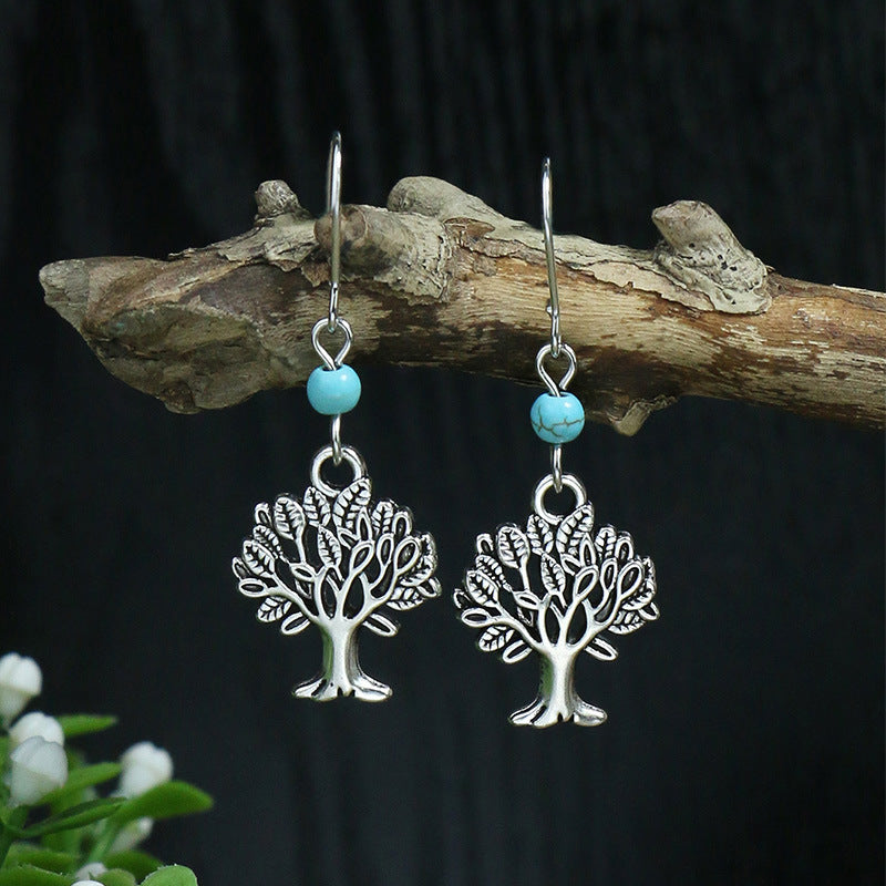 Silver tree-shaped earrings with turquoise beads on a dark background