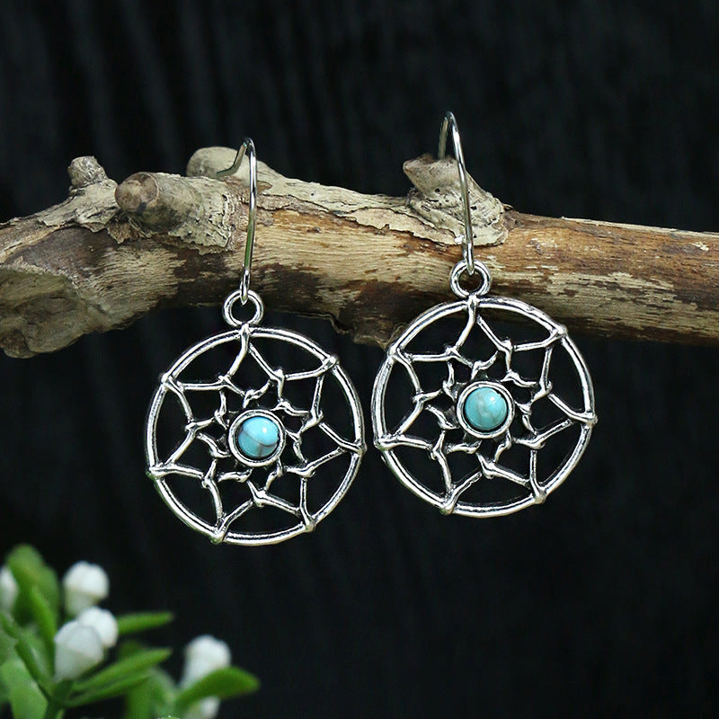 Silver earrings with turquoise stones on a branch against a dark background